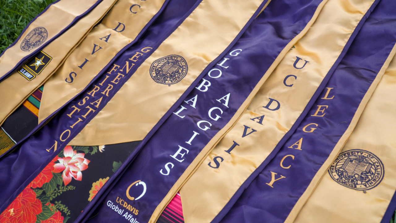 UC Davis graduate stoles showing the words "UC Davis", "First Generation" "Global Aggies" and "Legacy"