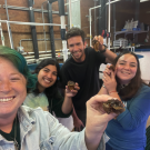 A group of four people holding up white abalone and smiling